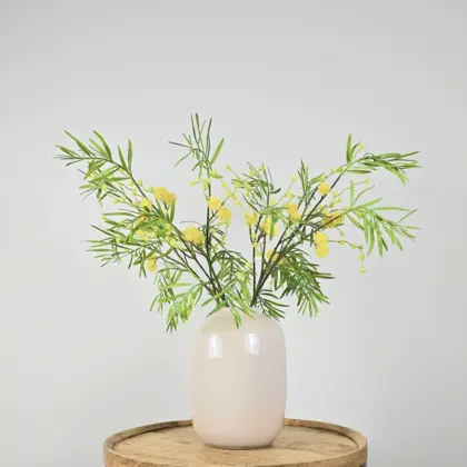 Kunstboeket met groen-gele mimosatakken in witte vaas