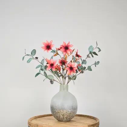 Zijden boeket in grijze vaas met groene eucalyptustakken en oranje-bruine dahlia bloemen