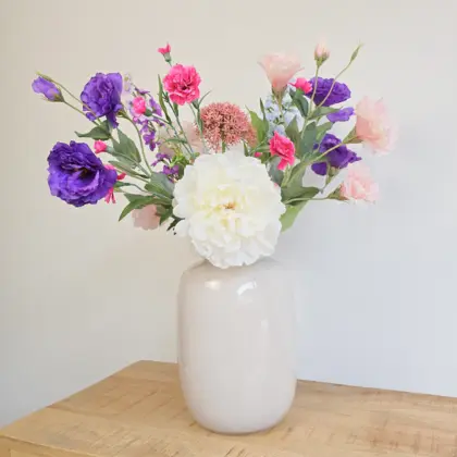 Zijden boeket met roze, witte, paarse en blauwe bloemen in witte vaas