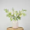 Kunstboeket met groen-gele mimosatakken in witte vaas
