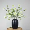 Zijden boeket met witte scabiosa bloemen en groene bladeren in zwarte vaas