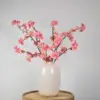 Zijden boeket met roze bloesemtakken in witte vaas