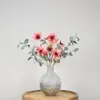 Zijden boeket in grijze vaas met groene eucalyptustakken en oranje-bruine dahlia bloemen
