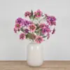 Zijden boeket met roze en paarse kunstbloemen met gouden accenten in witte vaas